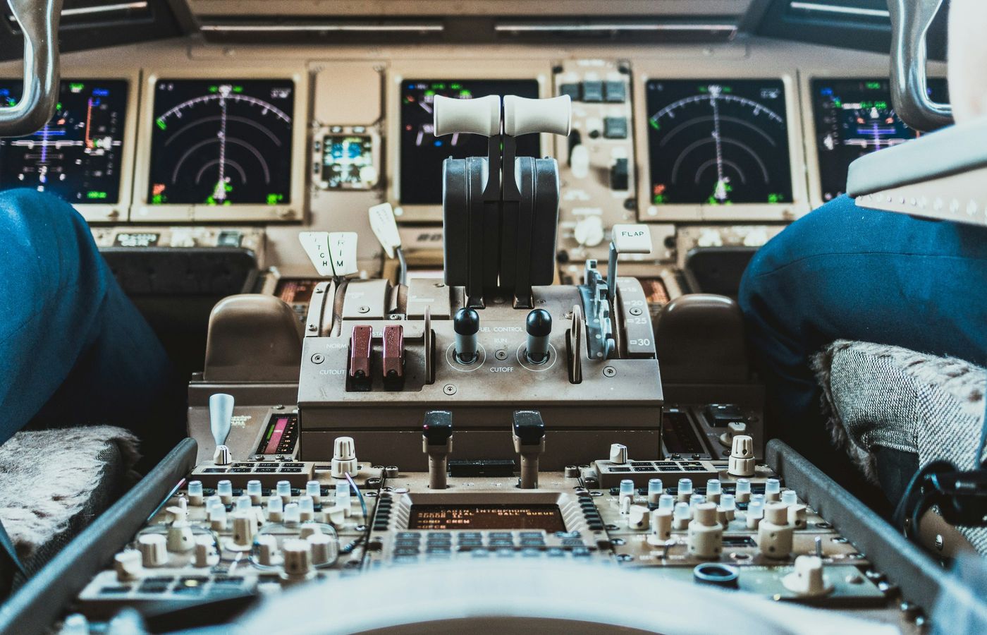Close up of the center console of an airplane with two pilots sitting each side.