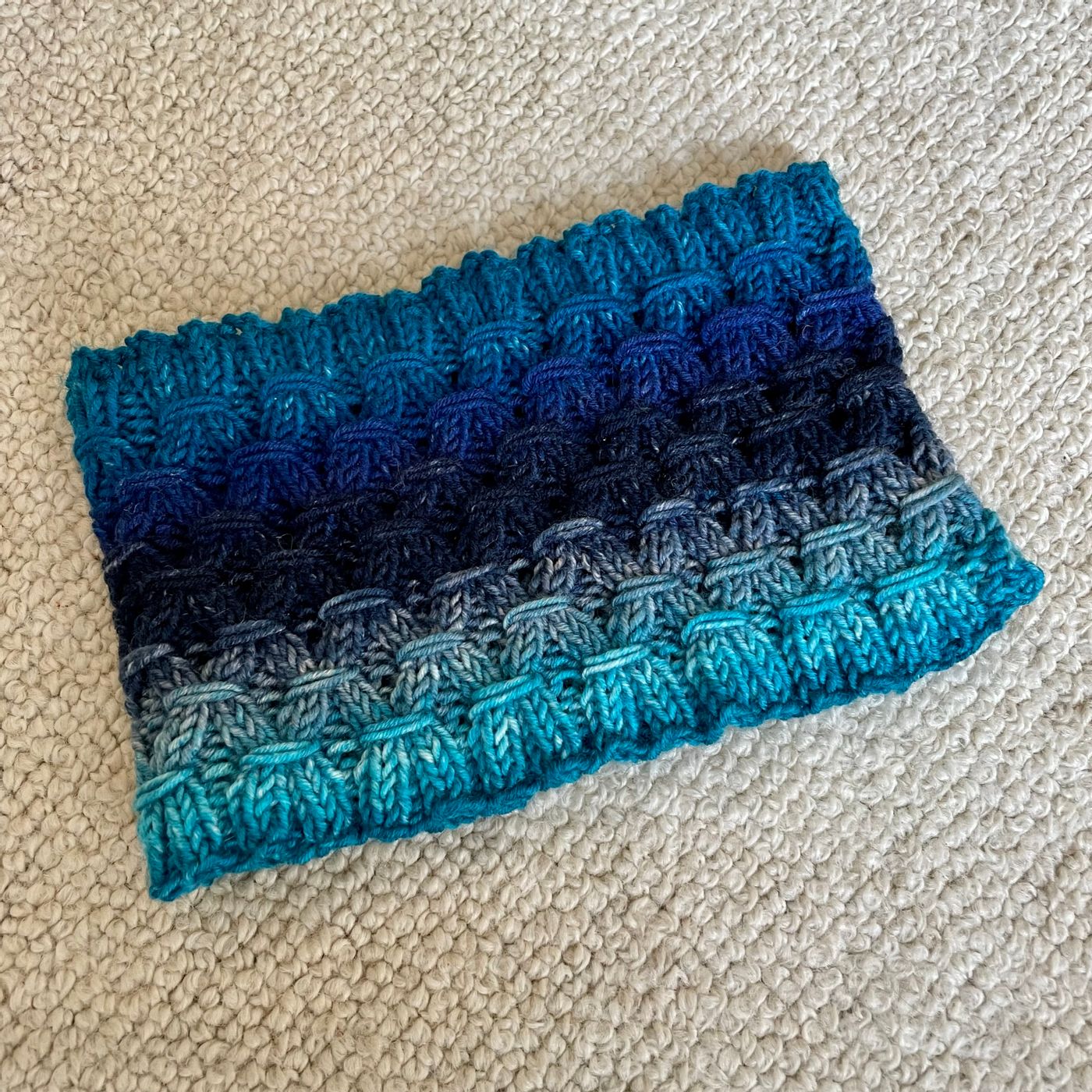completed multi shade blue cowl with a diamond shaped knitted pattern