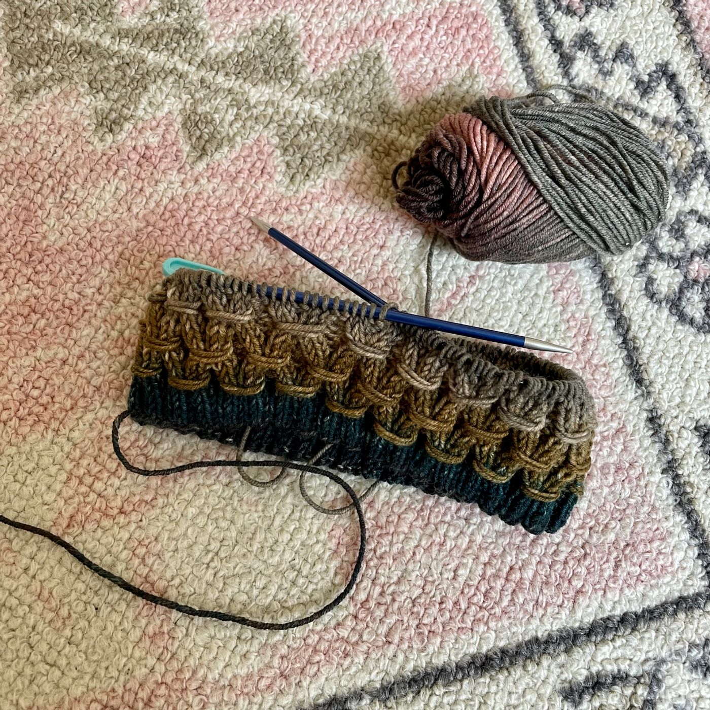 an in progress dark green, brown, and grey cowl with a diamond shaped knitted pattern